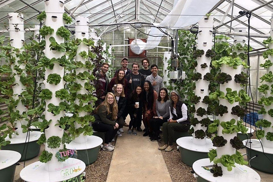 Volunteers at the TAMU Urban Farm United pose next to the planting towers.